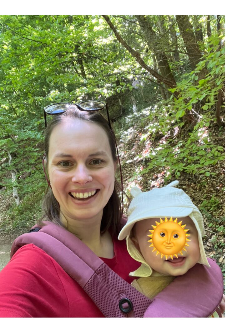Moeder met baby in draagzak in het bos aan het wandelen
